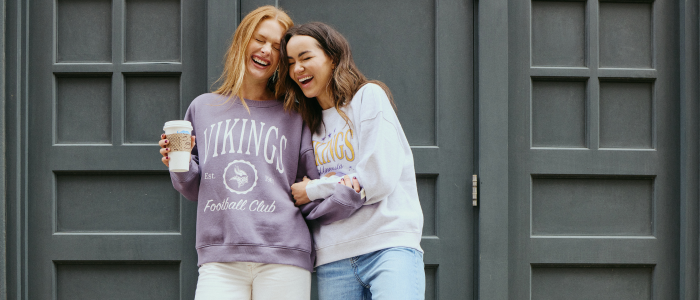 two women outside hugging and laughing in Vikings crew necks  in Minneapolis