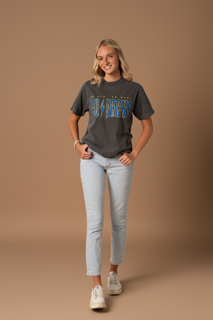 a full body image of a girl wearing jeans with faded black tee with Go Jacks screenprinted in blue and gold