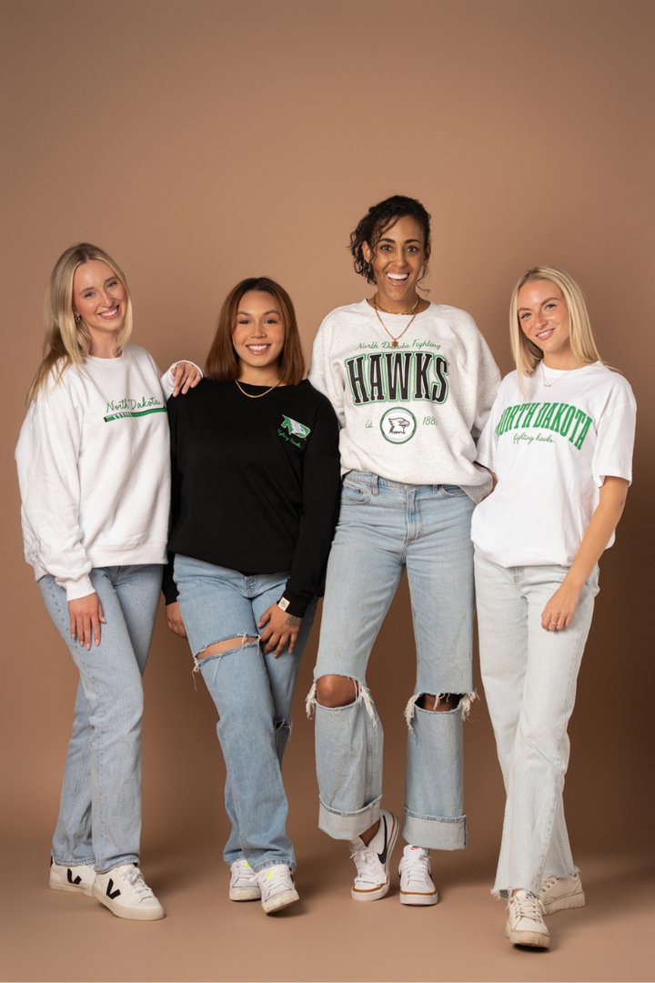 image of 4 girls standing together wearing 4 different UND Fighting Hawks styles
