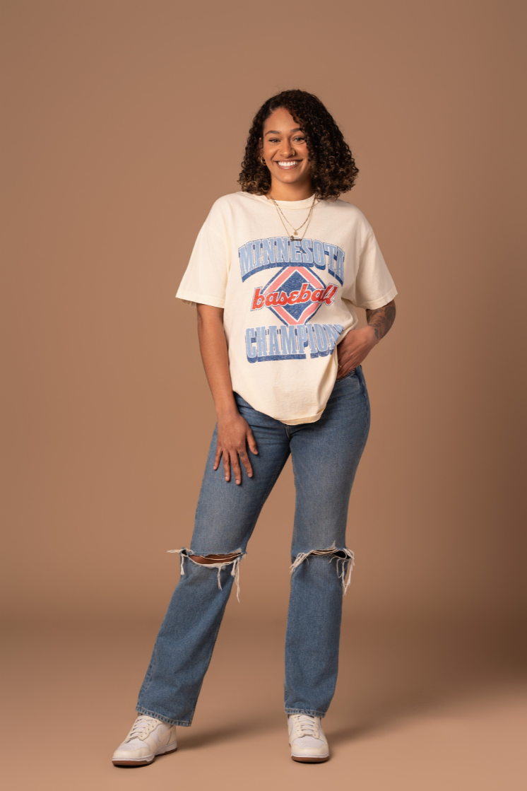 picture of a girl wearing cream colored cotton t-shirt with a red white and blue vintage inspired minnesota baseball screenprinted design