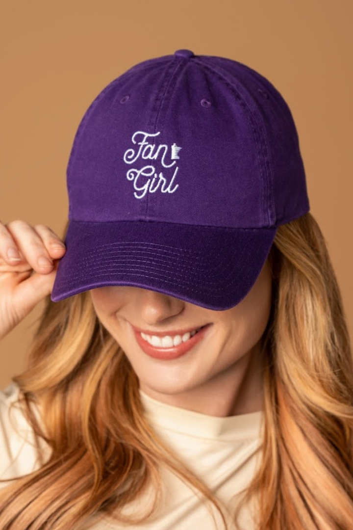 close up picture of a girl wearing a purple baseball hat with a white embroidered Fan Girl logo