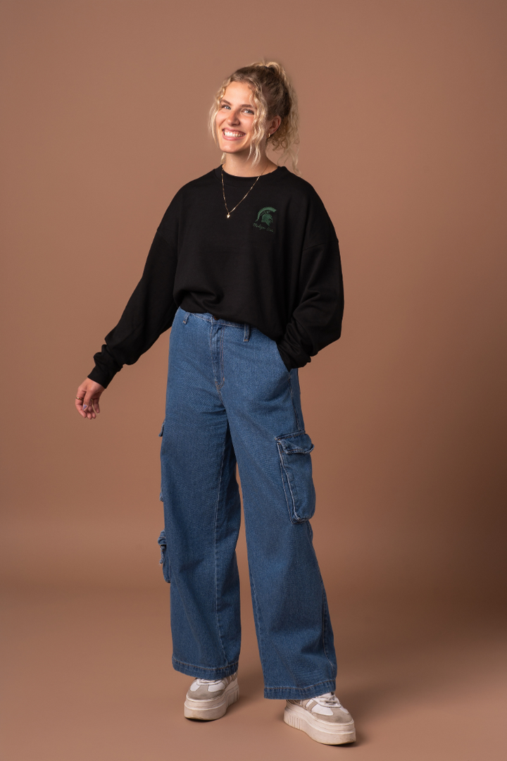 picture of a girl wearing a black Michigan State Supersoft Waist Length Crew Neck with a green embroidered  Spartan logo