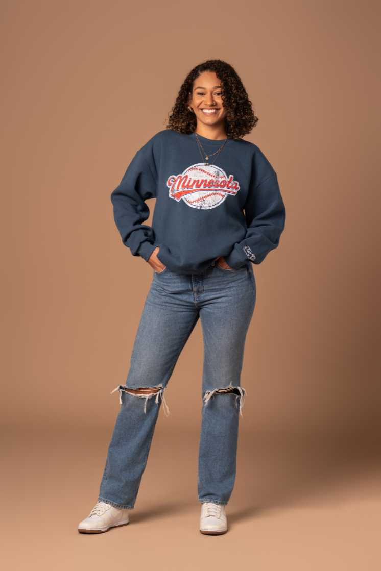 picture of a girl wearing a navy fleece-lined navy crew neck sweatshirt with a screenprinted minnesota baseball design