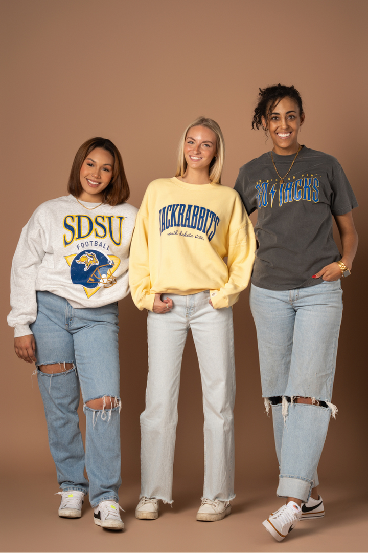 image of 3 girls standing together smiling all wearing a different South Dakota State crewneck or tshirt with blue and yellow screenprinted decoration