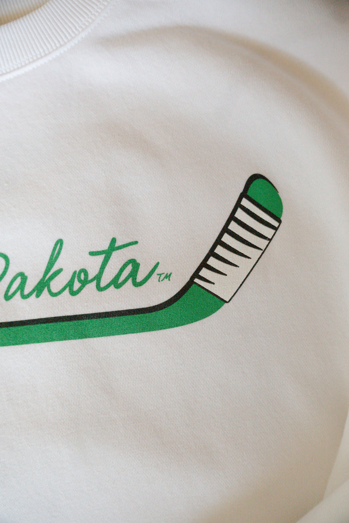 close up image of the hockey stick design in green with white and black taping at the end of the stick on a white crewneck
