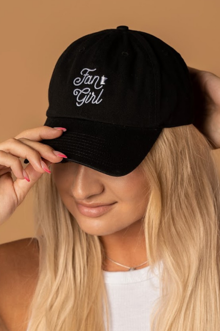 close up picture of a girl wearing a black baseball hat with a white embroidered Fan Girl logo