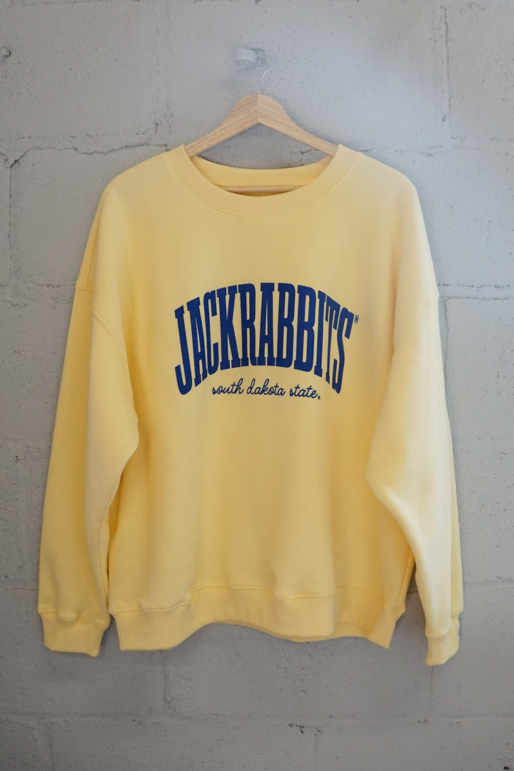 image of a yellow crewneck on a hanger with Jackrabbits written in blue and south dakota state in cursive written below in blue