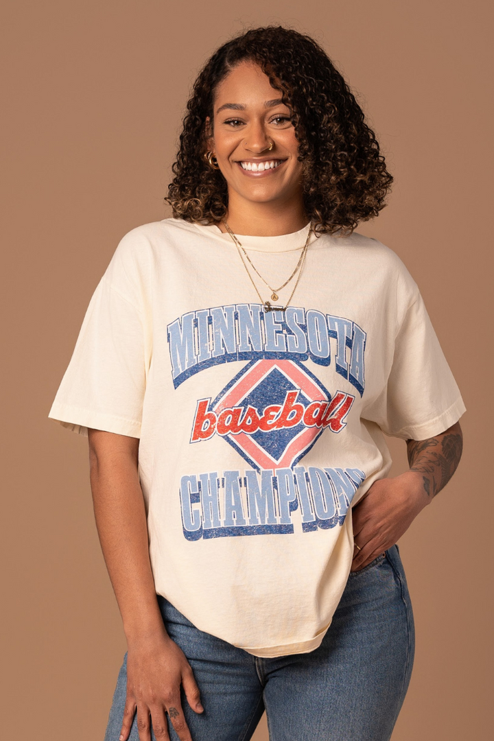 picture of a girl wearing cream colored cotton t-shirt with a red white and blue vintage inspired minnesota baseball screenprinted design