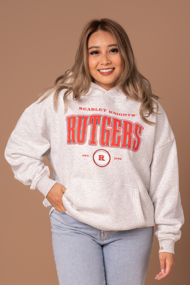 close up picture of a girl in a ash gray hoodie with a vintage inspired red, black, and white Rutgers University screenprinted design