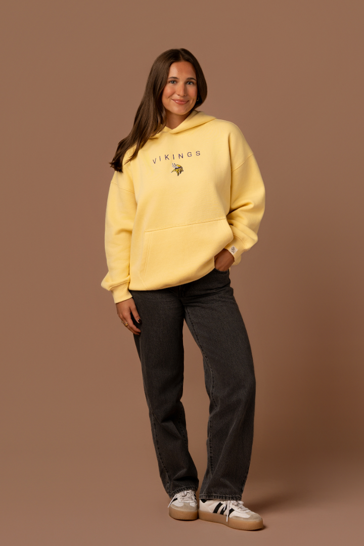 Woman wearing a yellow hoodie with purple 'Vikings' text and a small Vikings logo in the center
