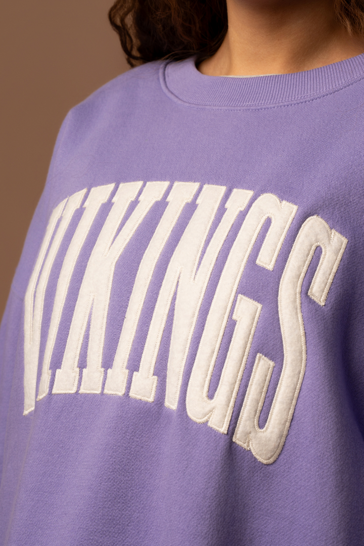 Purple crew neck sweatshirt with large, cream 'Vikings' text