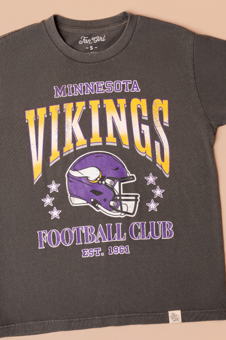 A faded black t-shirt with gold and purple 'Minnesota Vikings Football Club' and 'EST. 1961' text with a purple Vikings helmet graphic in the center