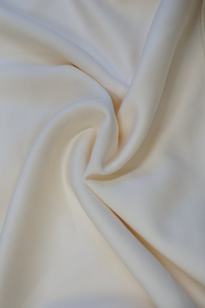 The fabric of an athleisure type ivory crew neck sweater that is twisted so you can better visualize how soft and quality the material is on the Fighting Illini Waist Length Crew Neck