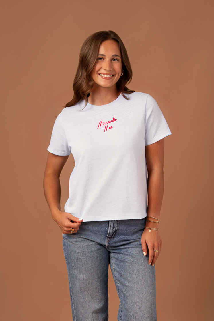 Woman wearing a white boxy cut t-shirt with red "Minnesota Nice" text