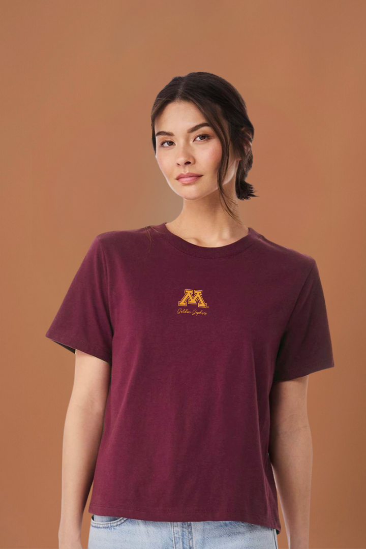 a women wearing a maroon cropped tee with a gold M and "golden gophers" written in script on the tee with a brown background