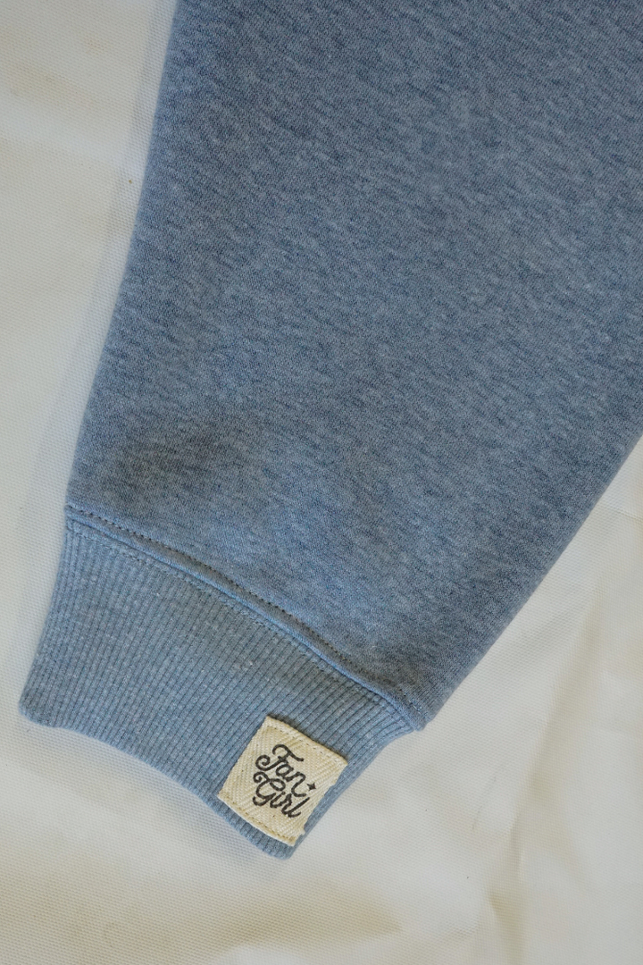 Close-up of a blue crew neck sweatshirt sleeve with a branded label