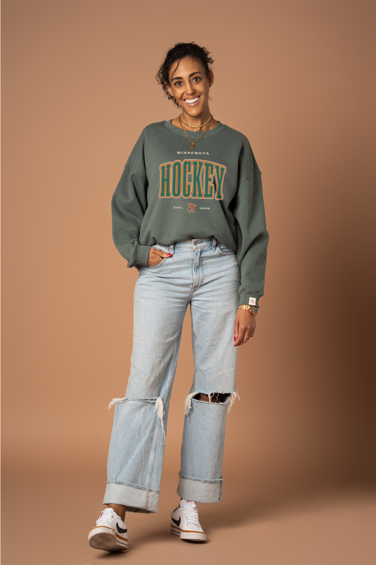 Woman wearing a green 'Minnesota Hockey' crew neck sweatshirt