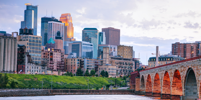 Minneapolis skyline surrounded by green trees and a river