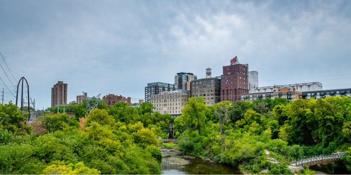 Minneapolis skyline surrounded by green trees and a river