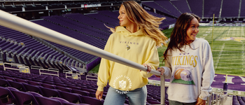 two girls walking up the steps at US Bank Stadium in Fan Girl x Minnesota Vikings Kickoff Collection hoodie and crew neck