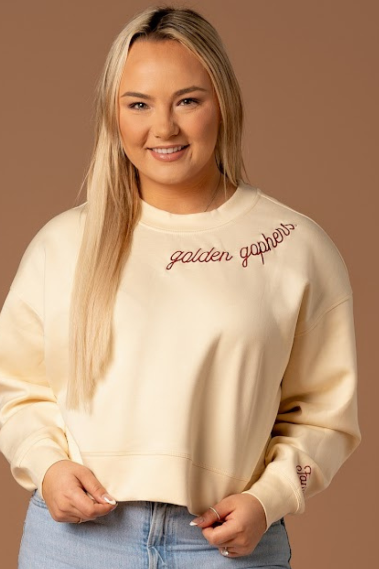 close up image of a girl wearing a black supersoft crewneck with golden gophers embroidered around the collar in maroon
