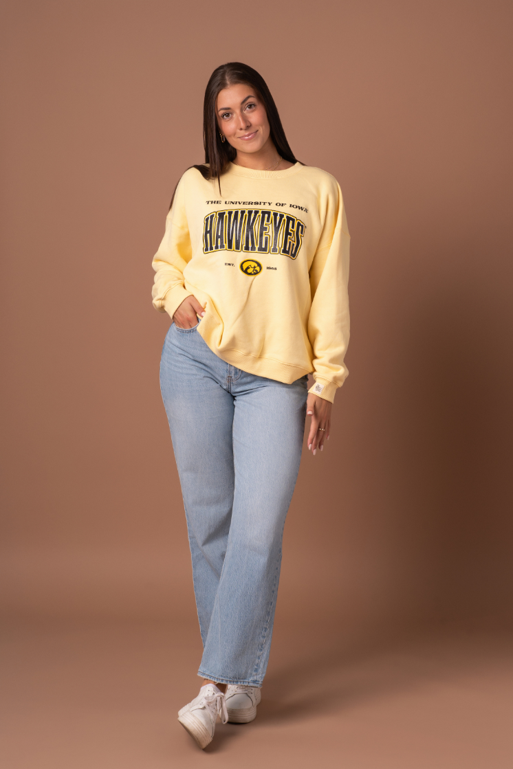 a girl wearing a pair of jeans and a yellow vintage university of iowa hawkeyes crew neck sweatshirt.