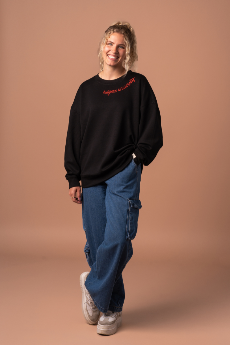 picture of a girl wearing a black  Supersoft Crew Neck, an athleisure material with red embroidered detail that says "Rutgers University"