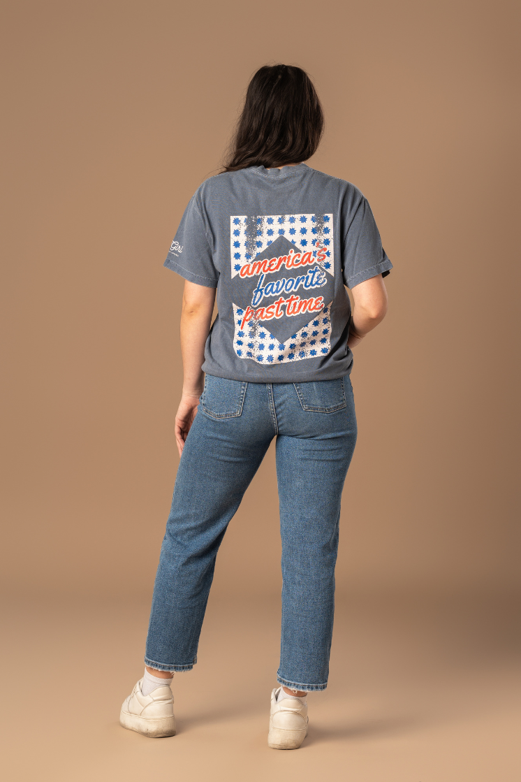 picture of the backside of a girl wearing a faded navy tee with red, cream, and blue vintage and worn-in inspired design 