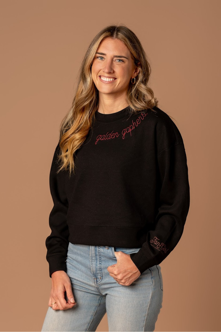 close up image of a girl wearing a black supersoft crewneck with golden gophers embroidered around the collar in maroon