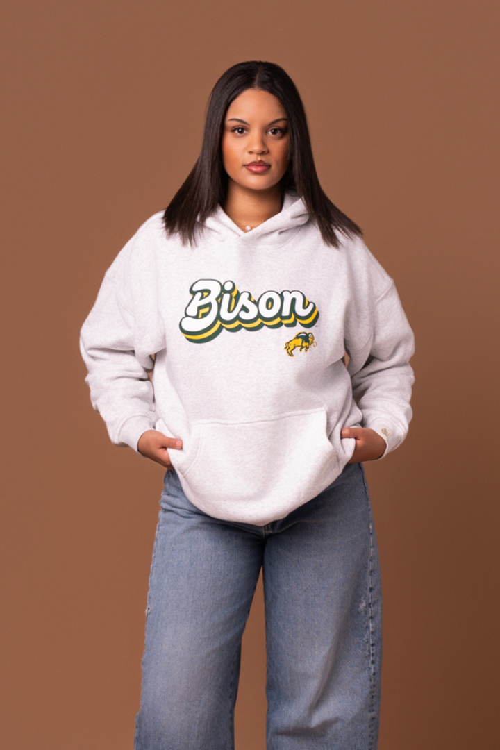 Women wearing a heather grey hoodie with 'Bison' text and a Bison logo under it 