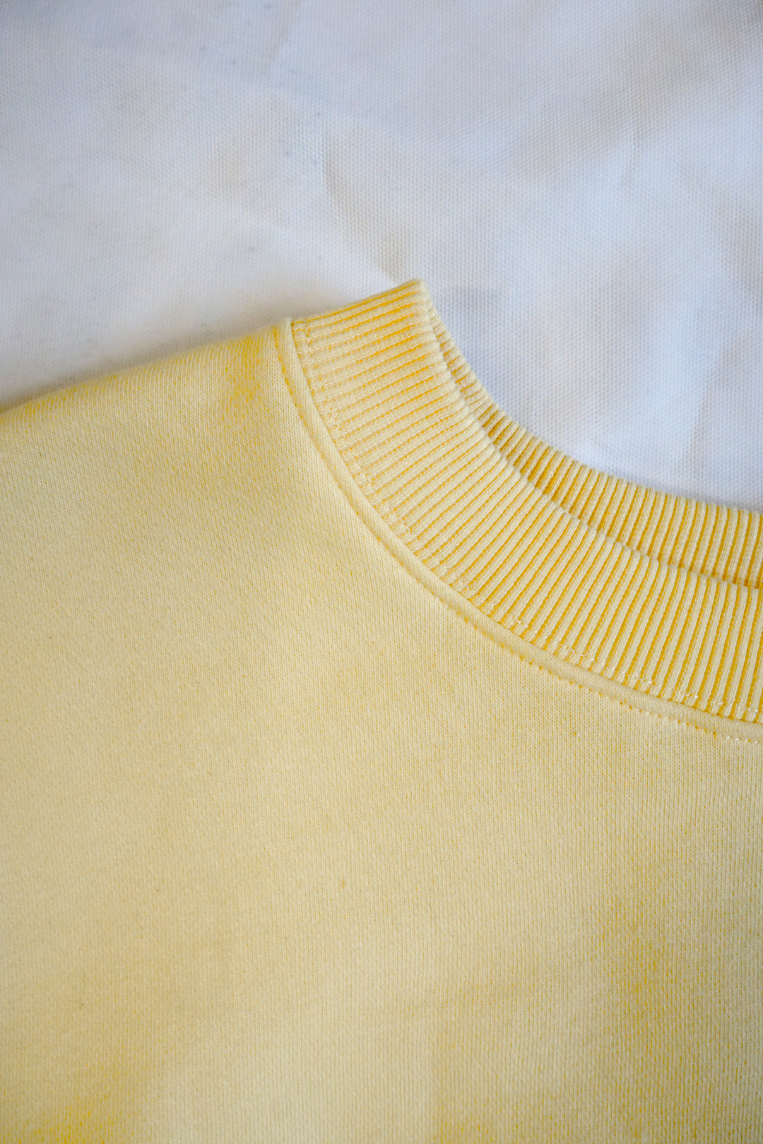 close up of the collar of a yellow crewneck high quality cotton material and looks very soft.