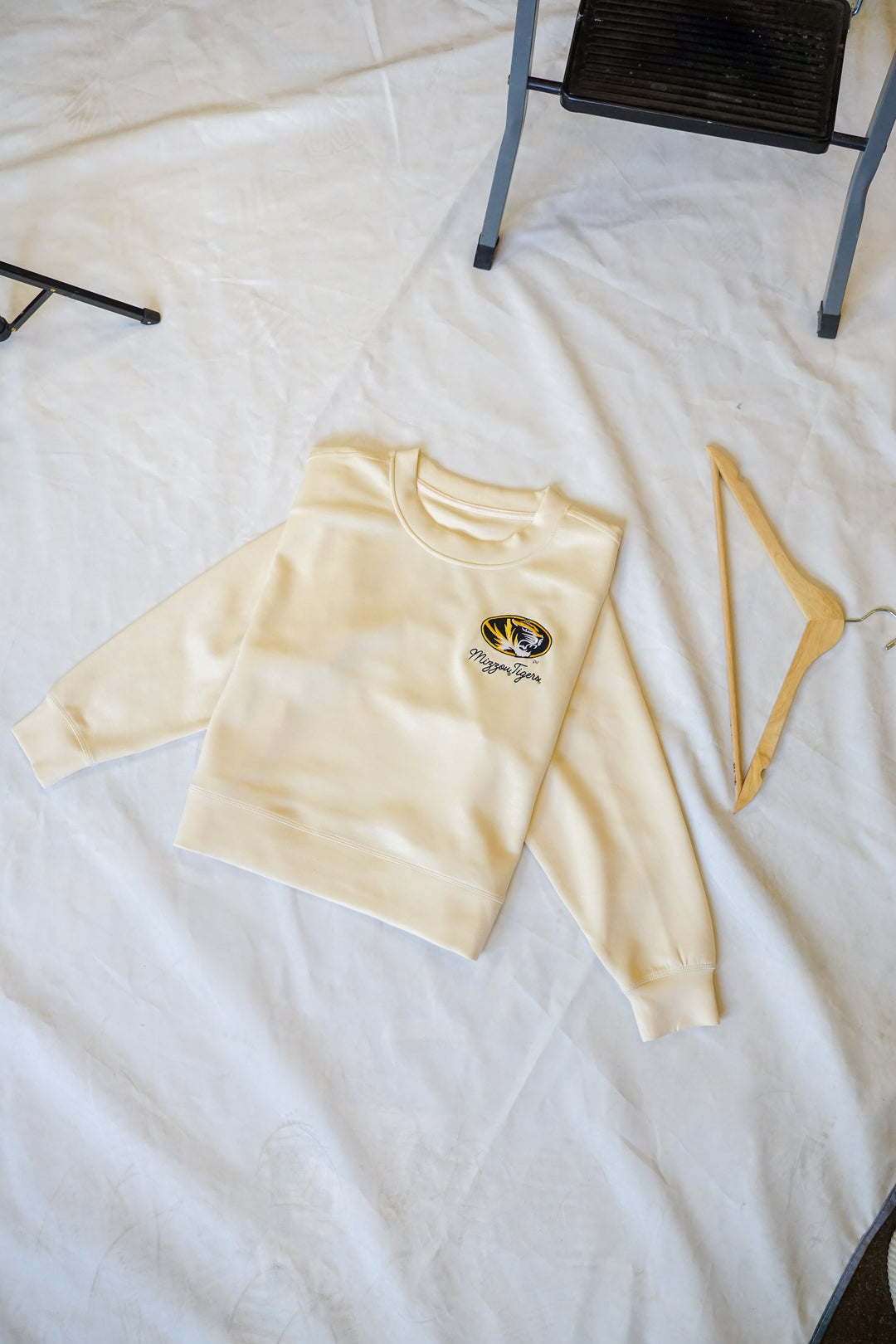 A flat lay photo of a bone colored crew neck with a Tigers logo on the upper chest.