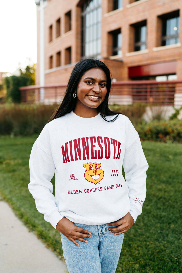 close up image of a girl around the UMN campus wearing an ash gray crewneck with Minnesota screenprinted across the chest with a Goldy head graphic below in maroon and gold detail