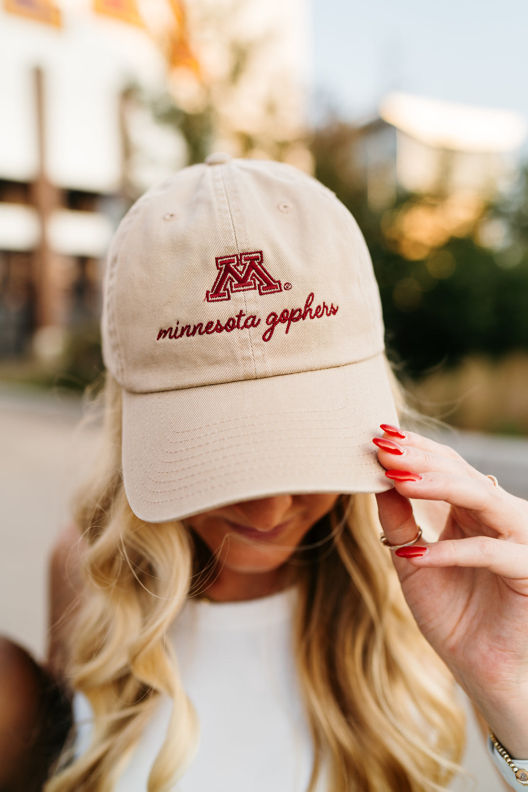 close up image of girl outside wearing a tan hat with an M and minnesota gophers embroidered in cursive in maroon