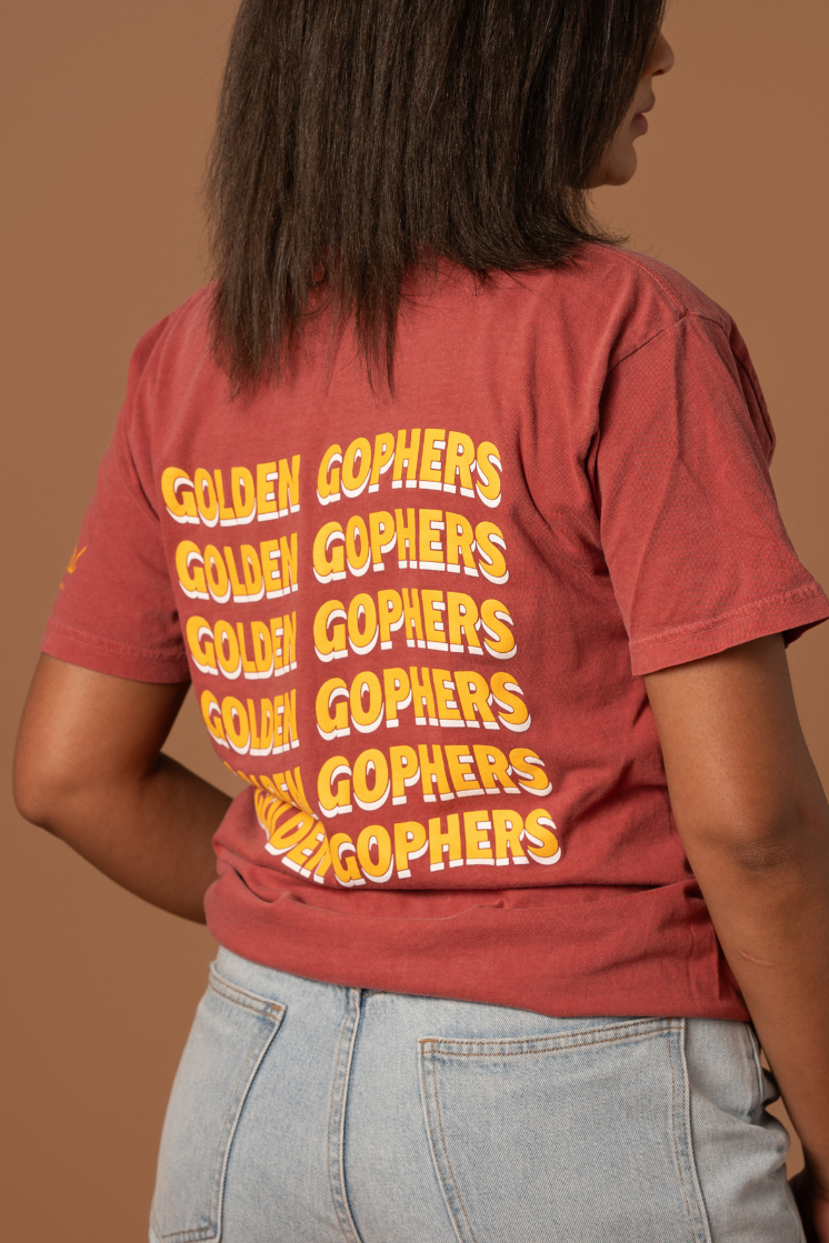 close up image of the back of girl wearing a crimson colored t-shirt with Golden Gophers screenprinted in gold that is stacked repeating six times