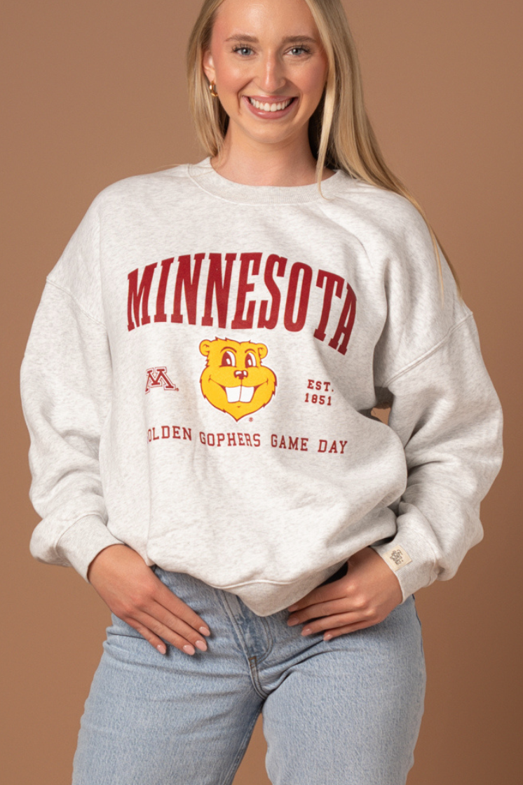 close up image of a girl wearing an ash gray crewneck with Minnesota screenprinted across the chest with a Goldy head graphic below in maroon and gold detail