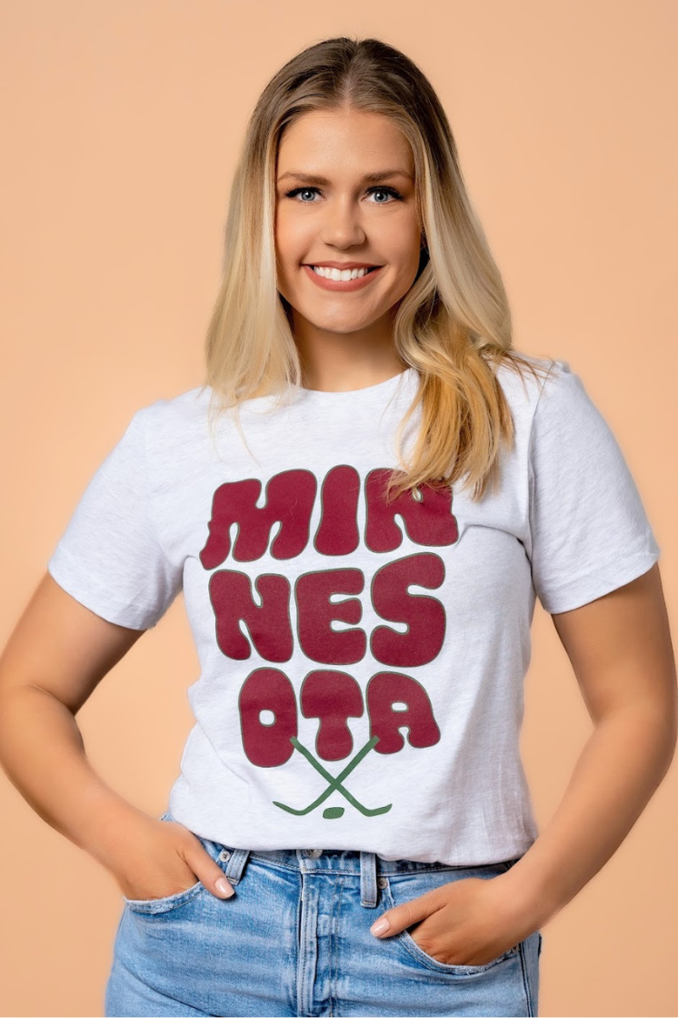 close up of a woman in a women's tshirt with bubble lettering that says minnesota hockey