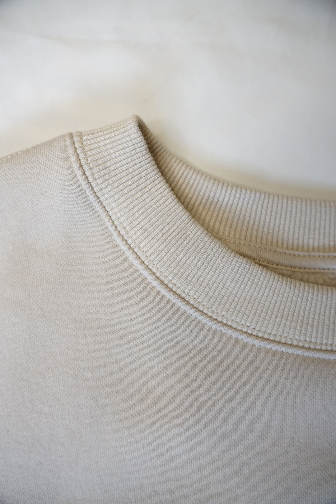 close up image of tan collar of a crewneck with a mock-neck like collar