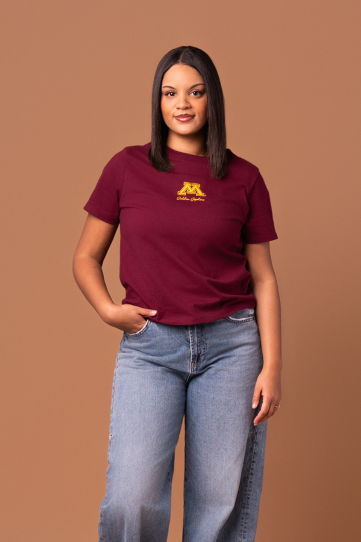 Woman wearing a maroon boxy t-shirt with a yellow 'Golden Gophers' text and a Minnesota logo 