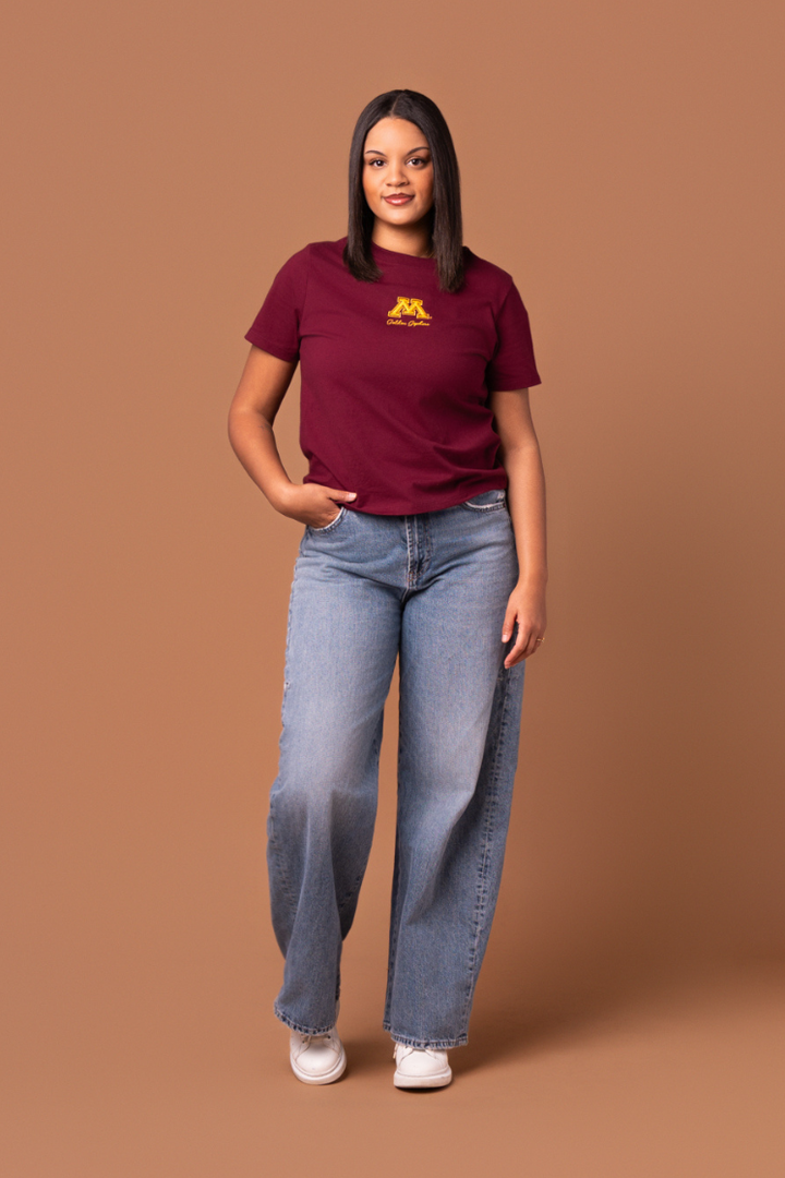 Woman wearing a maroon boxy t-shirt with a yellow 'Golden Gophers' text and a Minnesota logo 