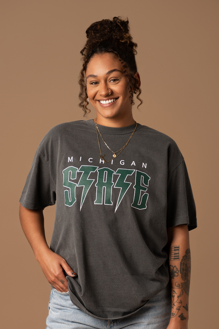close up picture of a girl wearing a faded black cotton Michigan State Spartans Vintage Band Tee with a green and white screenprinted graphic 