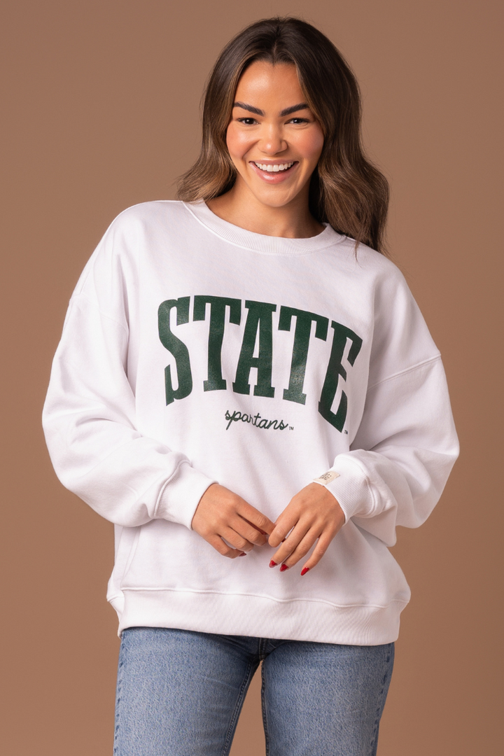 close up of a girl wearing a white Michigan State University Classic Crew Neck fleece lined sweatshirt with a green screenprinted design