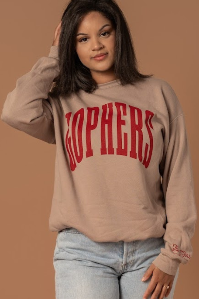 close up image of a girl wearing a tan colored crewneck with Gophers screenprinted maroon in big warped letters across the chest