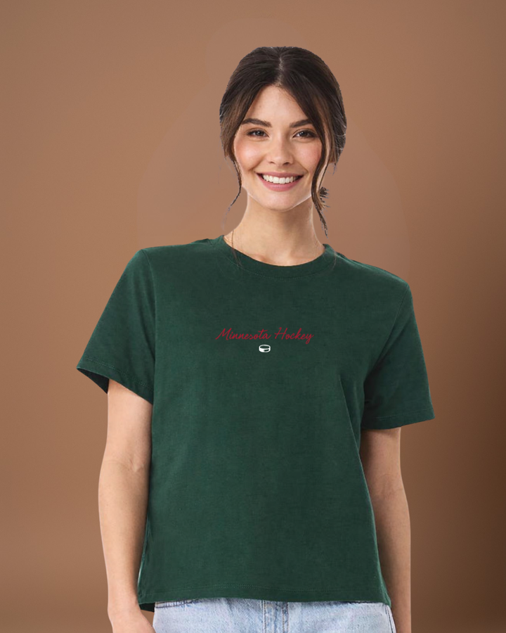 Woman wearing a green 'Minnesota Hockey' t-shirt on a brown background
