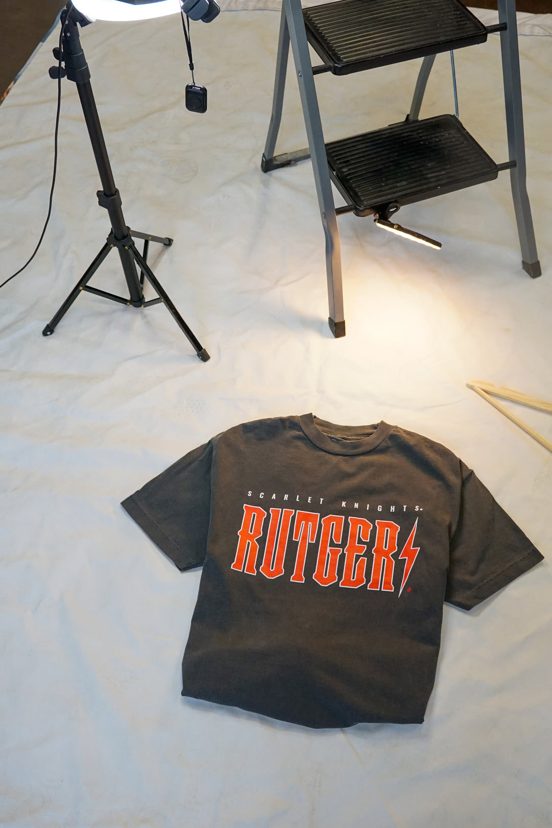 picture of a Rutgers University Vintage Band Tee on the ground with red and white screenprinited detail on a faded black cotton t-shirt