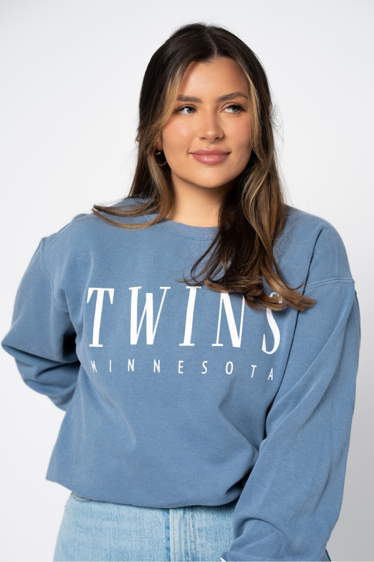 close up picture of a girl in a blue jean colored crew neck sweatshirt with white letter screenprinted detail