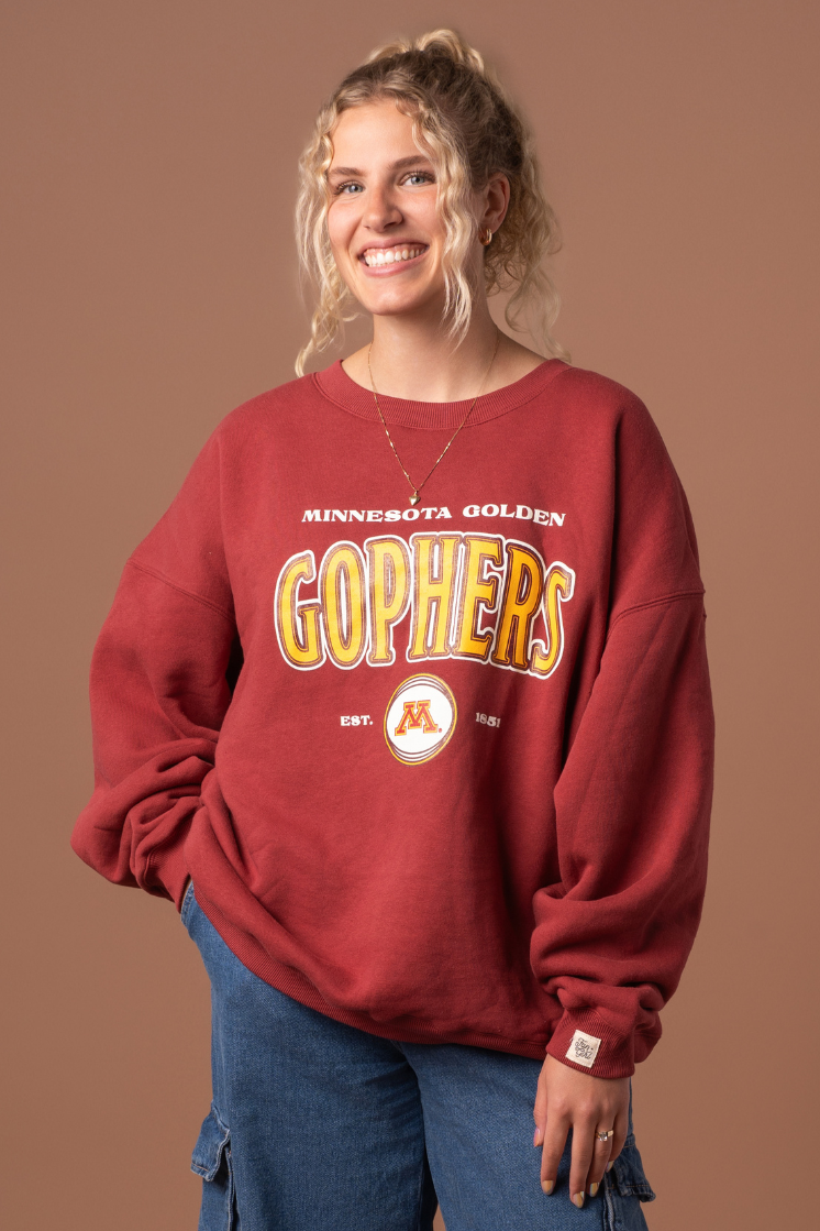 close up image of a girl wearing a maroon crewneck with Minnesota Golden Gophers screenprinted with a M logo in maroon, gold and white decoration