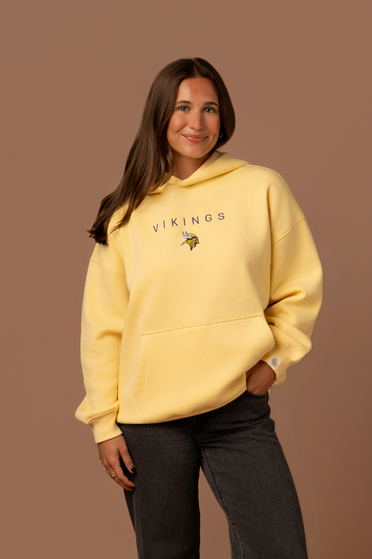 Woman wearing a yellow hoodie with purple 'Vikings' text and a small Vikings logo in the center