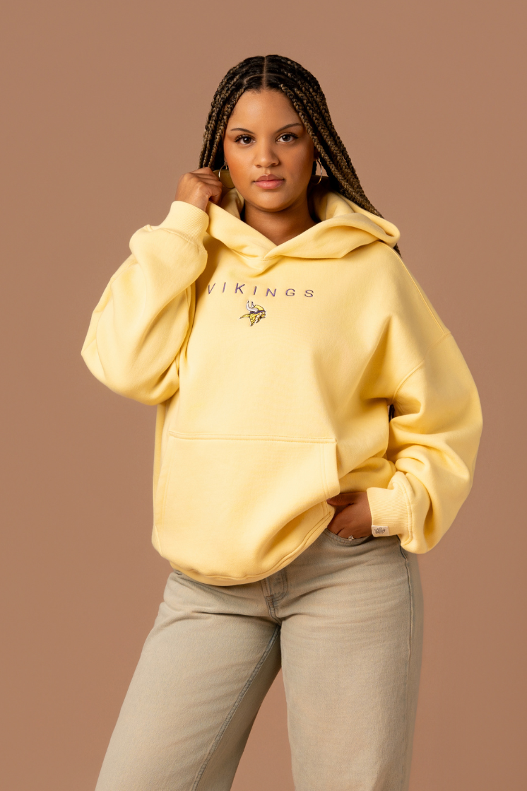 Woman wearing a yellow hoodie with purple 'Vikings' text and a small Vikings logo in the center