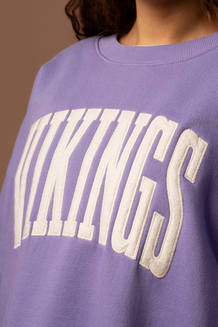 Purple crew neck sweatshirt with large, cream 'Vikings' text